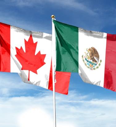 Mexican flag and Canadian flag on cloudy sky. flying in the sky