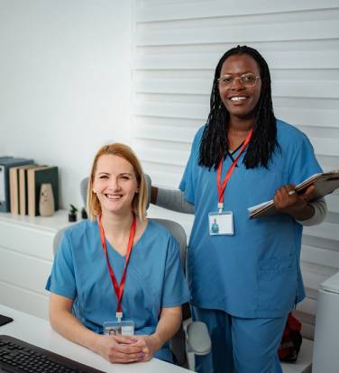 Two healthcare professionals smiling, collaborating in an office setting